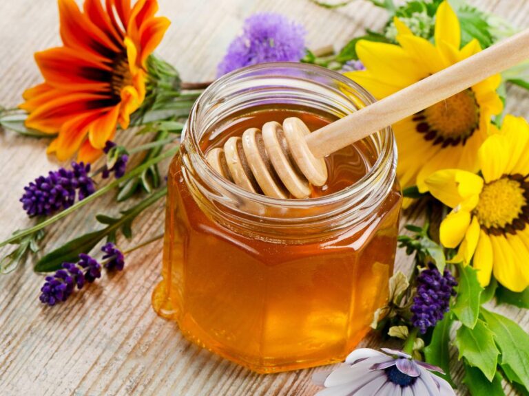 Słoik miodu z łyżeczką. Obrazek w artykule Łyżka do miodu. Jak wybrać najlepszą dla siebie łyżeczkę do miodu?