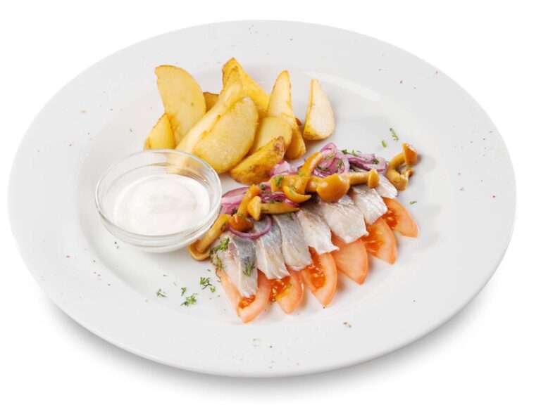 Talerz ze śledziami. Obrazek w artykule Śledzie z miodem. Przepis na pyszną przekąskę z filetów śledziowych i miodu