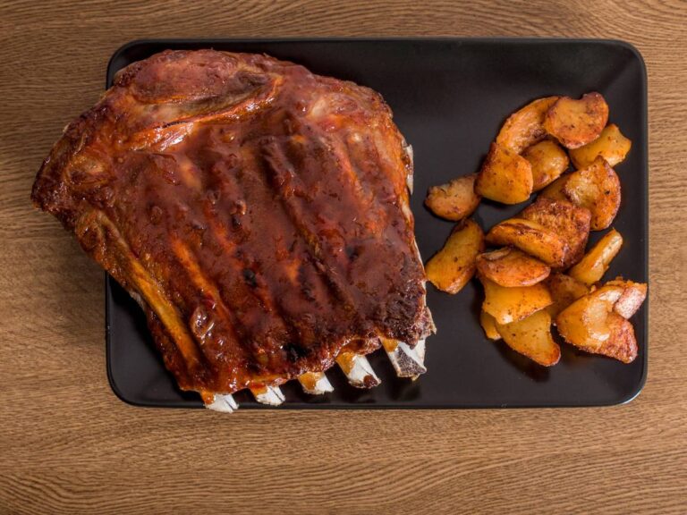 Talerz z pieczonymi żeberkami. Obrazek w artykule Marynata do żeberek z miodem: Przepis na pyszne, słodko-pikantne marynaty do pieczenia mięsa